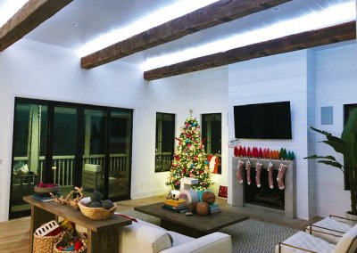Living room decorated for Christmas with accent lighting and automated fireplace.