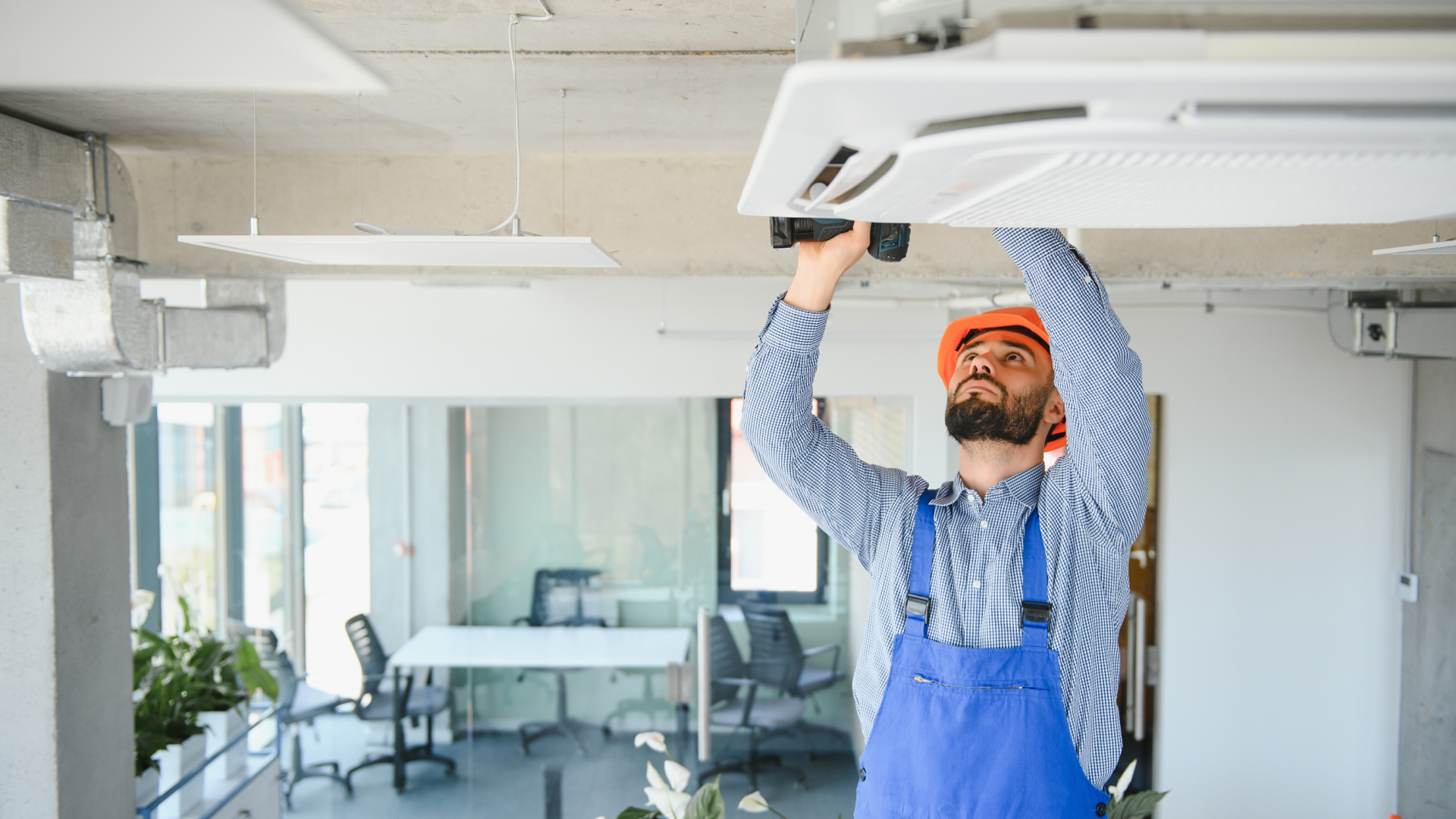 Afbeelding van een technieker die bezig is met sleutelen aan de airconditioning boven hem.